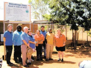 Historical photo: A group of nine staff and community members standing outside the Bidyadanga Clinic Clinic building.
