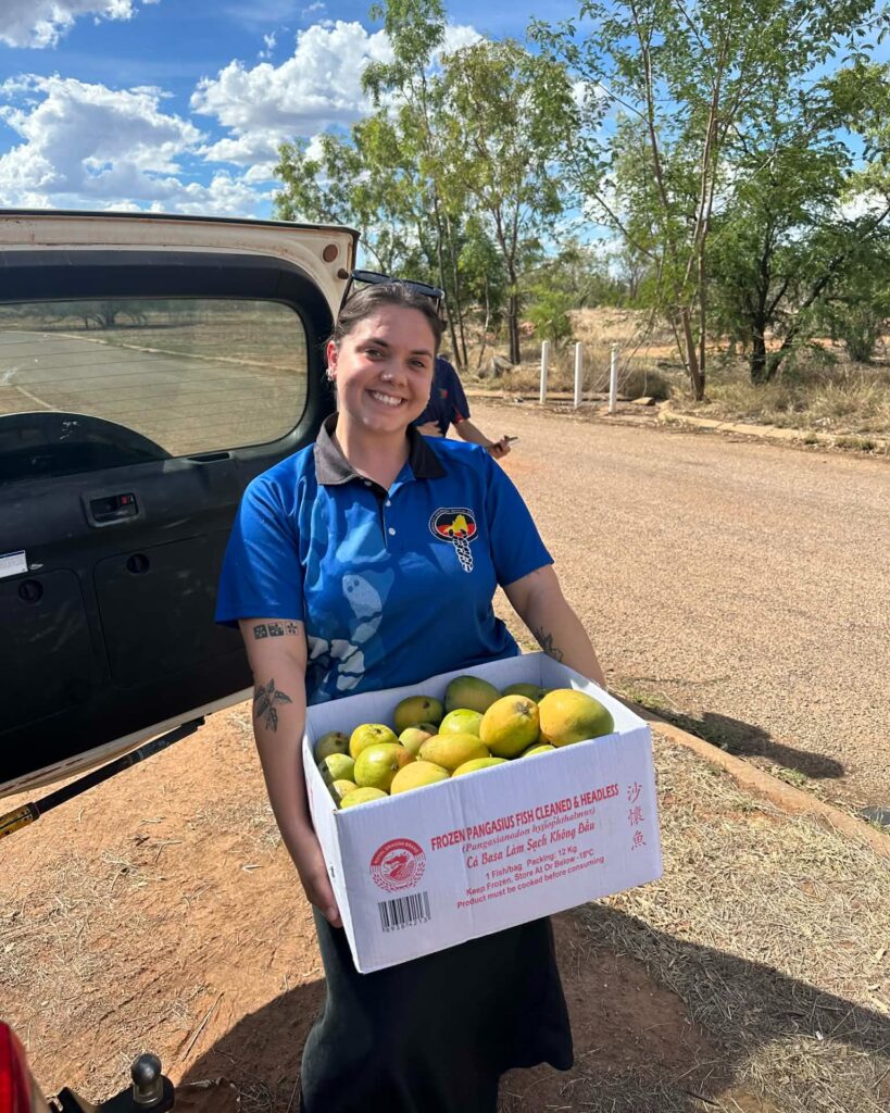 Staff member holding a large box of mangos.